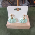 Mint pumpkin with gold stem stud dangle earrings on a wooden earring card stand