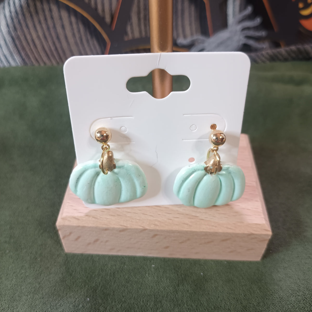 Mint pumpkin with gold stem stud dangle earrings on a wooden earring card stand