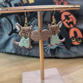 Brown mouse in mint green apron holding a cookie dangle earrings on a gold display stand
