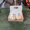 Cream pumpkin dangle earrings with silver ball stud on a wooden earring card stand